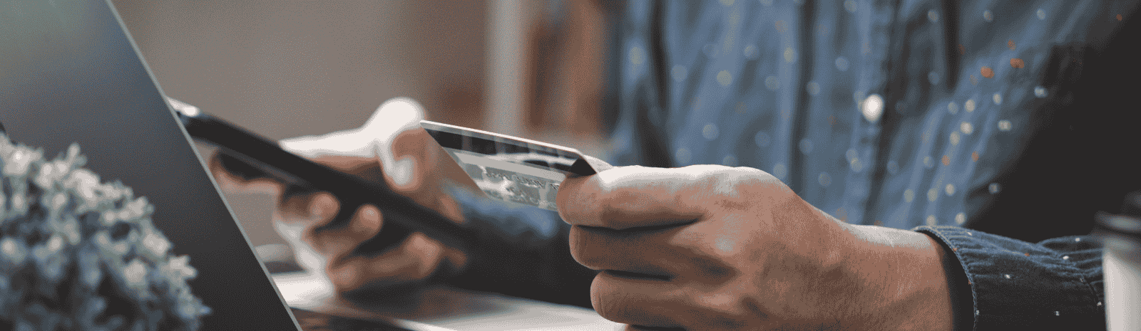 A person holding credit card in one hand and phone on the other.