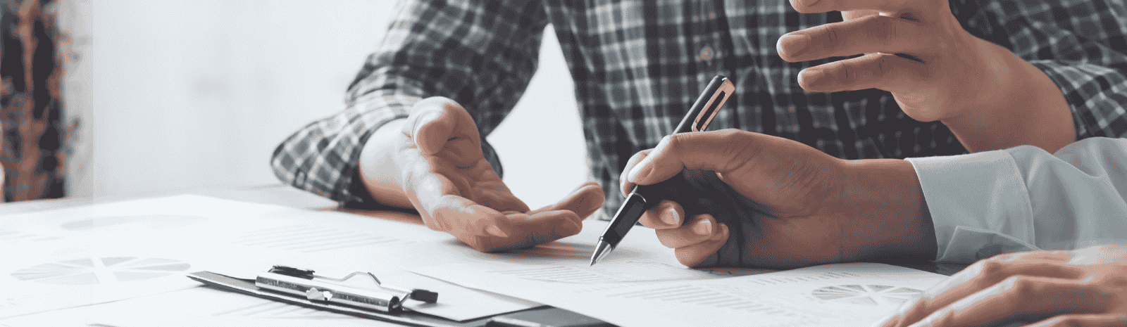 Two people sitting at a table with papers and pens