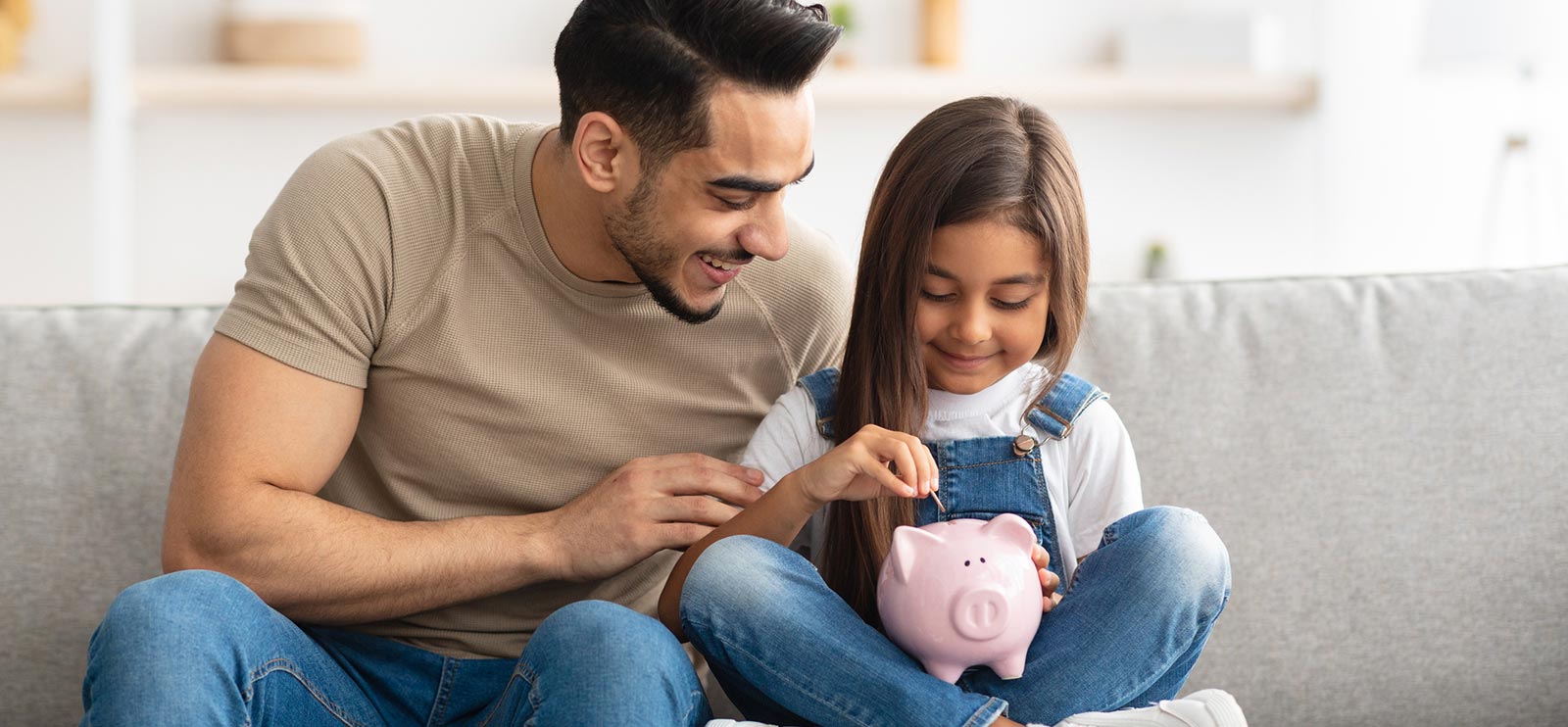 Father and daughter saving money in a piggy bank