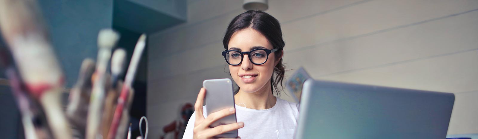 A lady using a smartphone and laptop computer in her studio