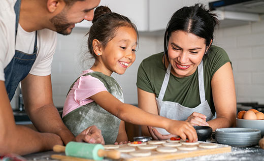 Parents with a daughter making cookies in their home