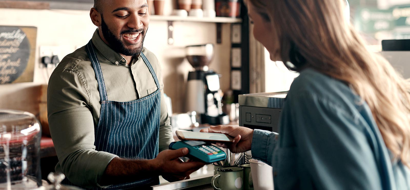 Lady making a purchase with her smartphone in a small business