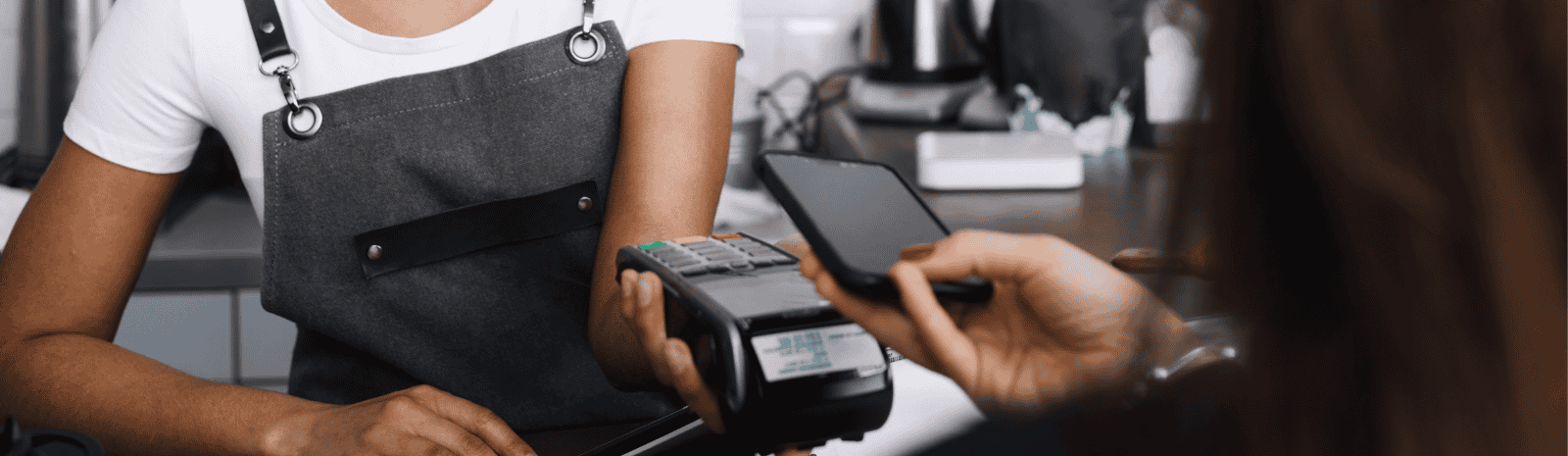 A person in an apron is using their phone to pay for something.